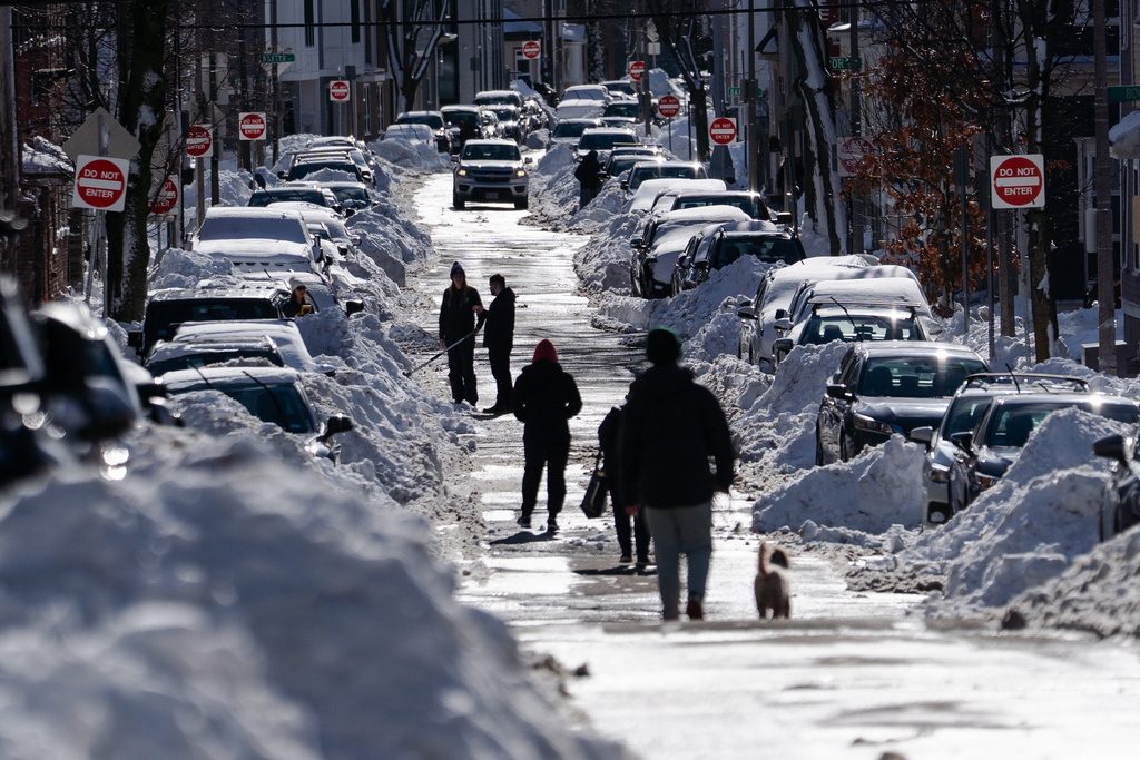 People opt to walk in the middle of the street over snowy sidewalks after a snowstorm, Tuesday, Feb. 24, 2026, in South Boston. (AP Photo/Sophie Park)