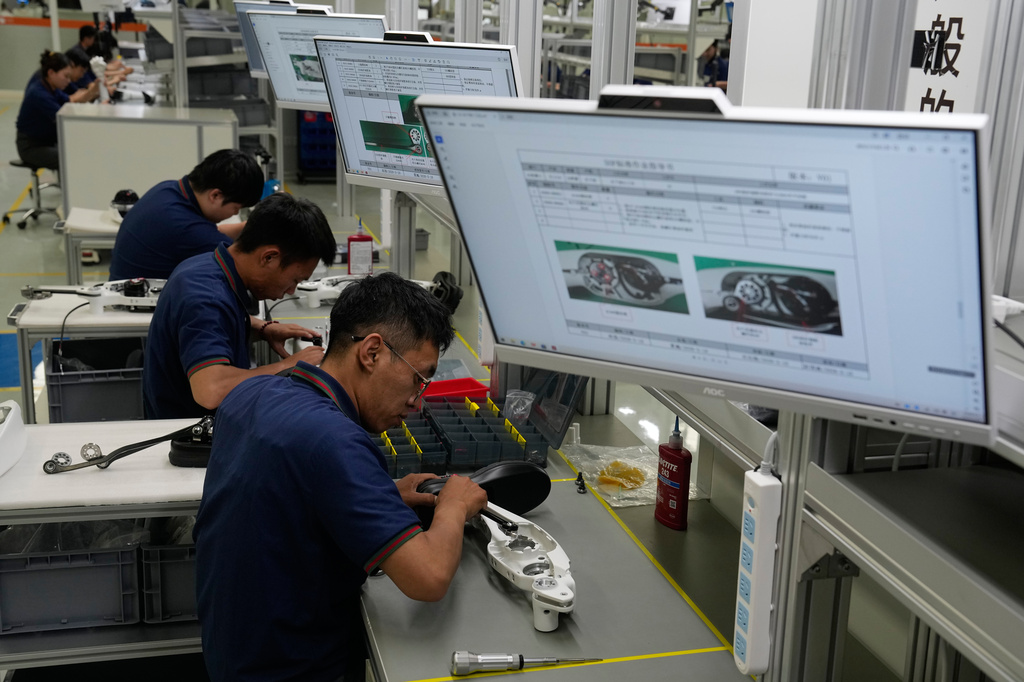 Workers assemble robot legs components at the LY iTech Beijing Super Factory for Embodied Artificial Intelligence during a media tour in the Beijing E-Town on the outskirts of Beijing on May 29, 2026. (AP Photo/Andy Wong)