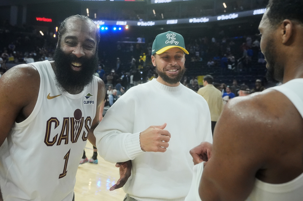 Injured Golden State Warriors guard Stephen Curry, middle, smiles while talking with Cleveland Cavaliers guard James Harden (1) and guard Donovan Mitchell after an NBA basketball game in San Francisco, Thursday, April 2, 2026. (AP Photo/Jeff Chiu)