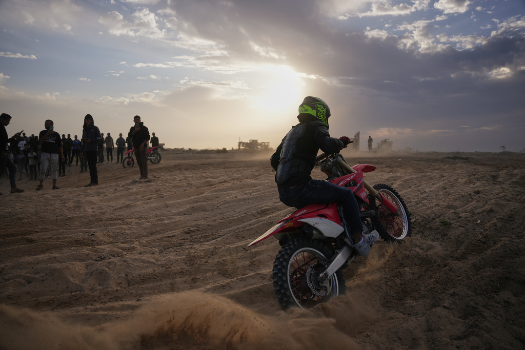 Palestinian Ahmed Abu Amra, 23, rides his motorcycle and shows off his skills on a sandy hill in the Al-Zahra area, central Gaza Strip, Friday, Dec. 5, 2025. (AP Photo/Abdel Kareem Hana)