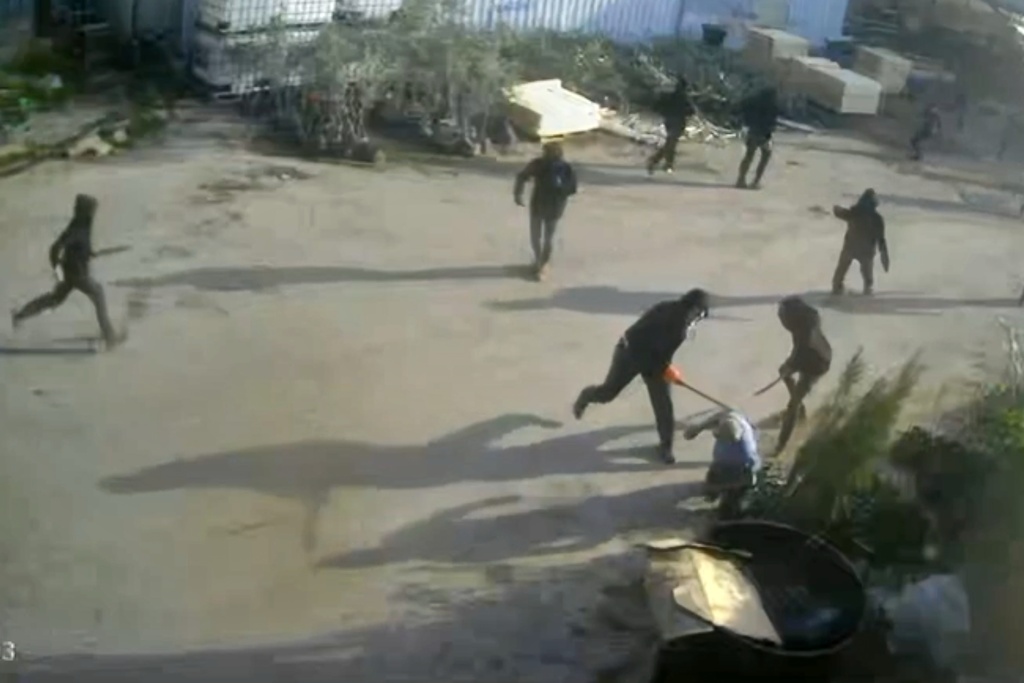 This frame grab from security camera footage filmed Jan. 8, 2026, and obtained by The Associated Press, shows men dressed mostly in black with their faces covered, two of whom are hitting a man on the ground as he tried to flee a nursery in the northern West Bank village of Deir Sharaf. Two people who witnessed the attack and are members of the family that owns the facility said the assailants were Israeli settlers beating 67-year-old Basim Saleh Yassin.(UGC via AP)