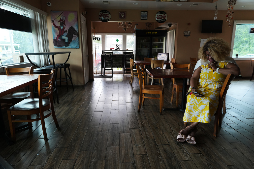 Marjorie Estimé waits for a food order at the Caribbean Creole Café in Salisbury, Md., Sunday, Aug. 2, 2026. (AP Photo/Luis Andres Henao)