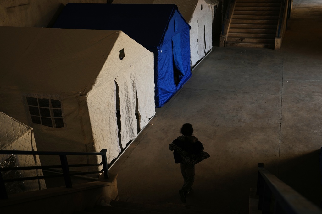 A displaced child plays past tents set up inside the Camille Chamoun Sports City Stadium, which has been turned into a shelter for people displaced by Israeli airstrikes in southern Lebanon and Dahiyeh, Beirut's southern suburbs, in Beirut, Lebanon, Tuesday, March 10, 2026. (AP Photo/Hassan Ammar)