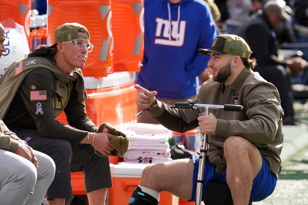 New York Giants' injured players Cam Skattebo and Jaxson Dart talk before an NFL football game against the Green Bay Packers Sunday, Nov. 16, 2025, in East Rutherford, N.J. (AP Photo/Seth Wenig)