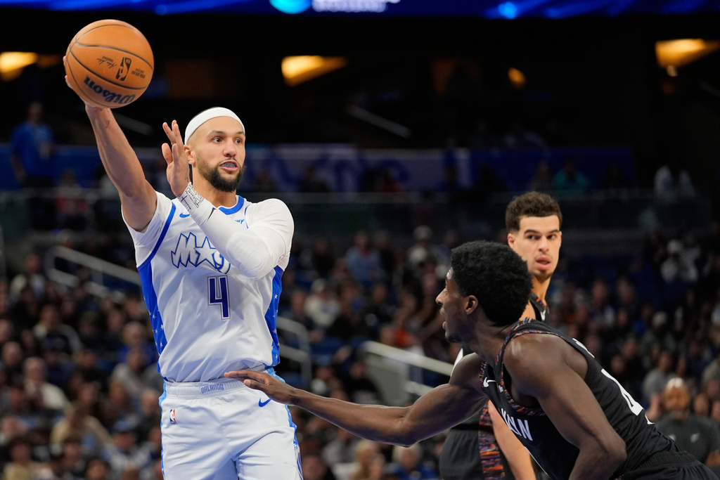 Orlando Magic guard Jalen Suggs (4) passes the ball over Brooklyn Nets guard Drake Powell, right, during the second half of an NBA basketball game, Thursday, Feb. 5, 2026, in Orlando, Fla. (AP Photo/John Raoux)