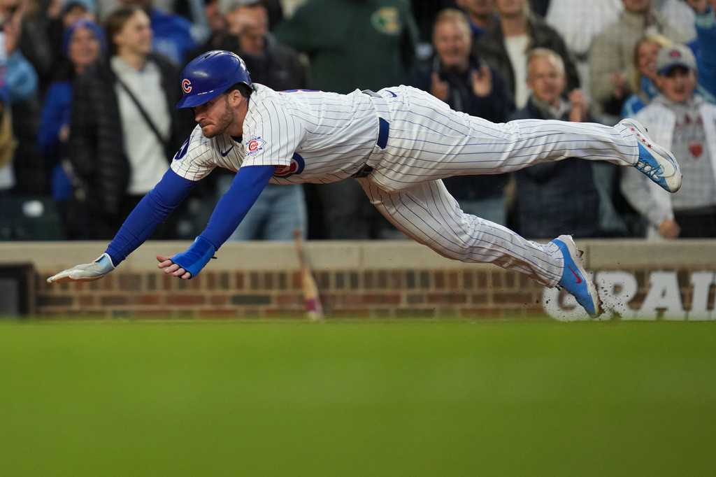 Chicago Cubs' Ian Happ (8) dives into home to score on a double from Seiya Suzuki (27) during the fourth inning of a baseball game against the Cincinnati Reds, Wednesday, May 6, 2026, in Chicago. (AP Photo/Erin Hooley)