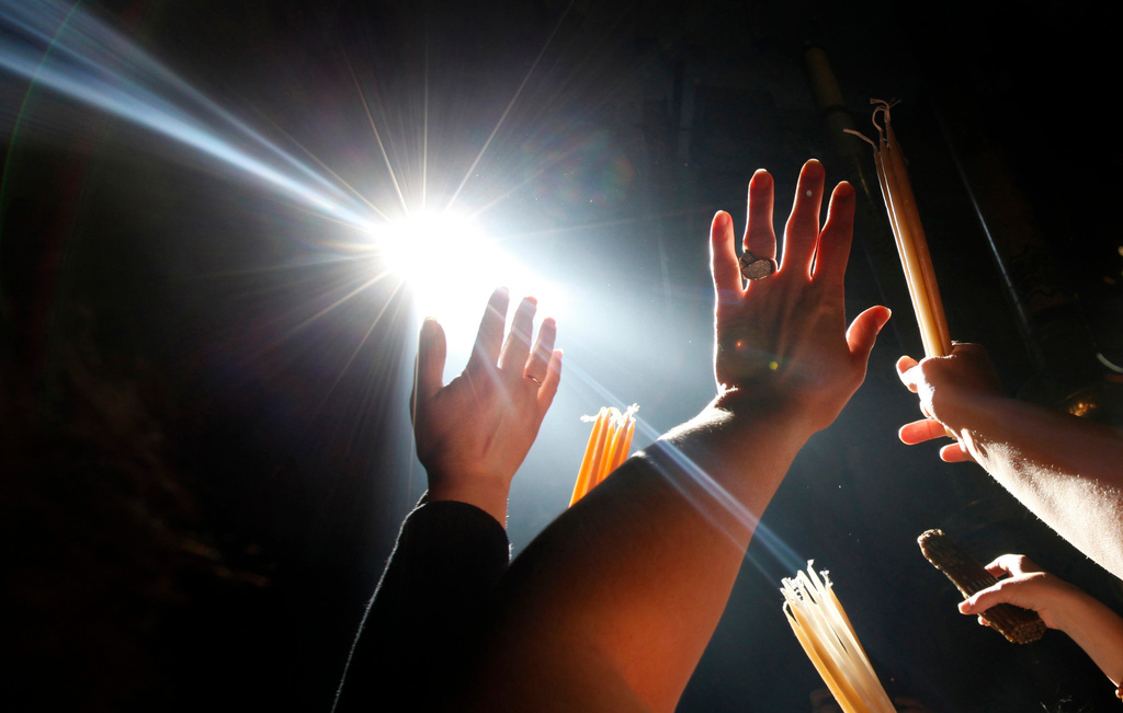 FILE - Christian Orthodox pilgrims raise their hands towards a beam of light in front of the Edicule at the Church of the Holy Sepulcher during the ceremony of the Holy Fire in Jerusalem's Old City, Saturday, April 18, 2009. (AP Photo/Kevin Frayer, File)