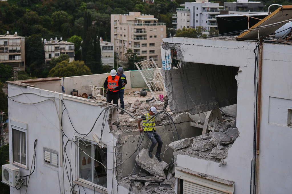 Israeli authorities inspect a damaged house following an Iranian missile strike in Haifa, Israel, Monday, March 30, 2026. (AP Photo/Ariel Schalit)