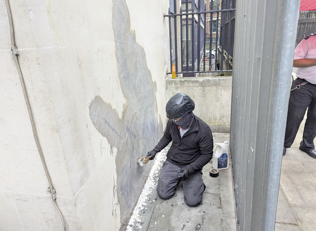 A worker removes the new artwork by Banksy, which shows a judge attacking a protester with a gavel, after it appeared at the Royal Courts of Justice in London on Monday, on Wednesday, Sept. 10, 2025. (Danny Halpin/PA via AP)