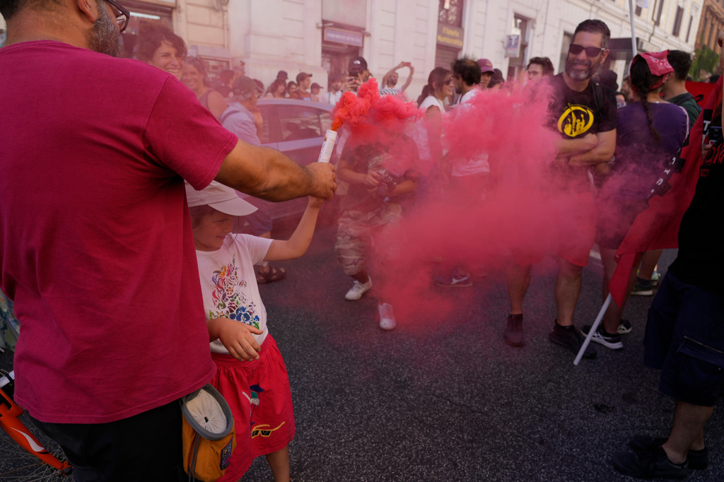 Demonstrators light flares during a march in Rome, Saturday, June 13, 2026, to protest Italy's security and migration package, including a migrant "repatriation bonus" scheme criticized by opposition parties and legal groups as unconstitutional and ethically problematic. (AP Photo/Gregorio Borgia)