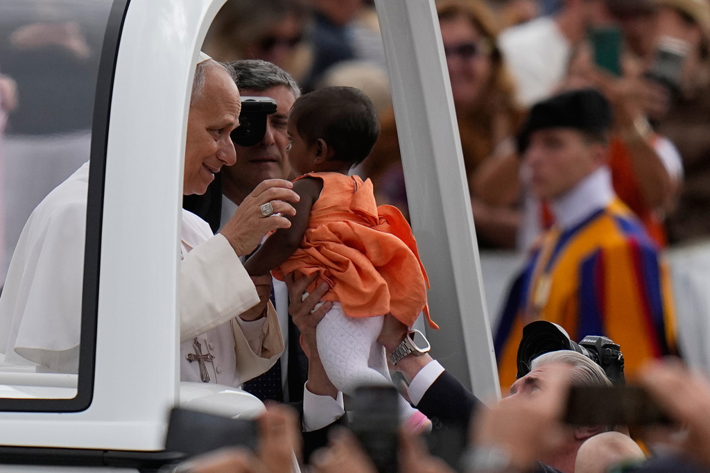 Pope Leo XIV blesses a little girl as he arrives for his weekly general audience in St. Peter's Square, at the Vatican, Wednesday, May 13, 2026. (AP Photo/Alessandra Tarantino)