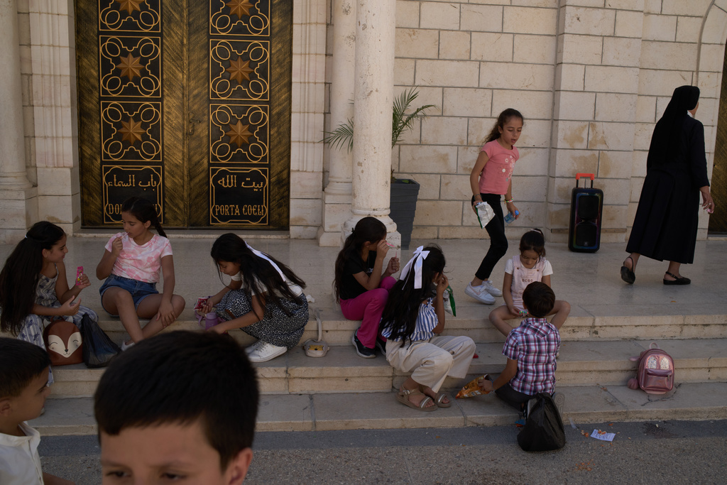 Palestinian youths chat and listen to music outside Christ the Redeemer Church after attending morning Mass in the West Bank village of Taybeh, Sept. 28, 2025. (AP Photo/Leo Correa)