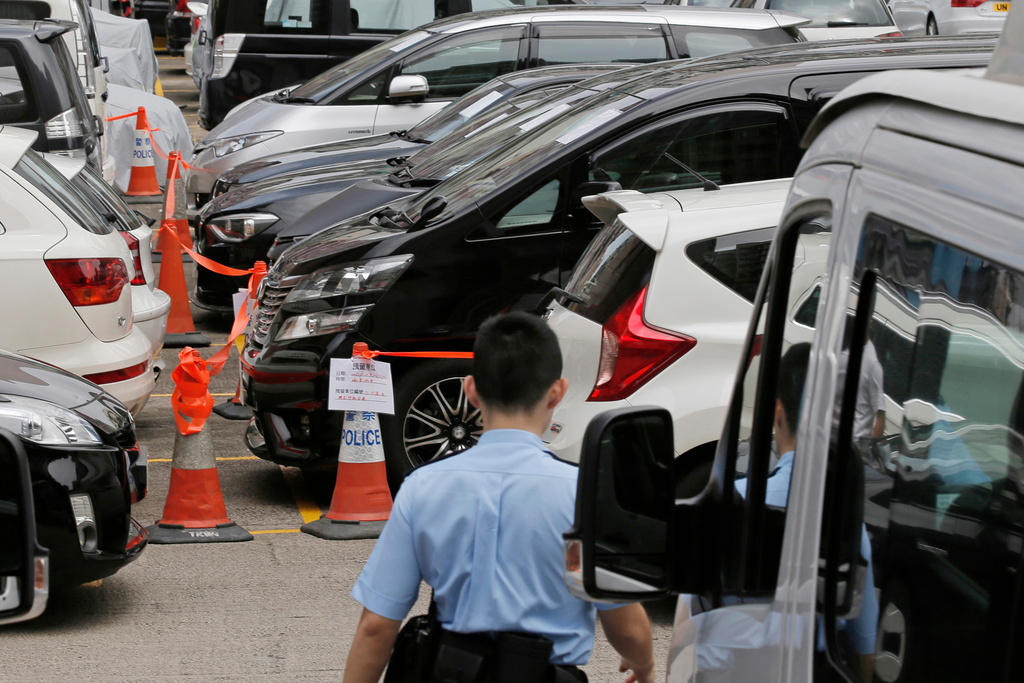 FILE - Impounded vehicles meant for Uber service, center, are parked behind a police cordon line at a police station in Hong Kong, on May 23, 2017. (AP Photo/Kin Cheung, File)