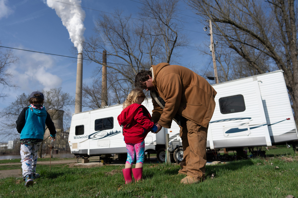 John White Jr. helps his daughter, Paisley, 3, zip her hoodie as his son, Malachi, 5, walks outside their home at the Lock 24 RV Park and Campground in Racine, Ohio, Saturday, March 14, 2026, across the Ohio River from the coal-fired Mountaineer Power Plant, near New Haven, W.Va. “In a winter season, I can say I pay a lot and honestly do not know how I do it. It has been hard,” said White Jr. who struggles to pay his utility bills. (AP Photo/Carolyn Kaster)