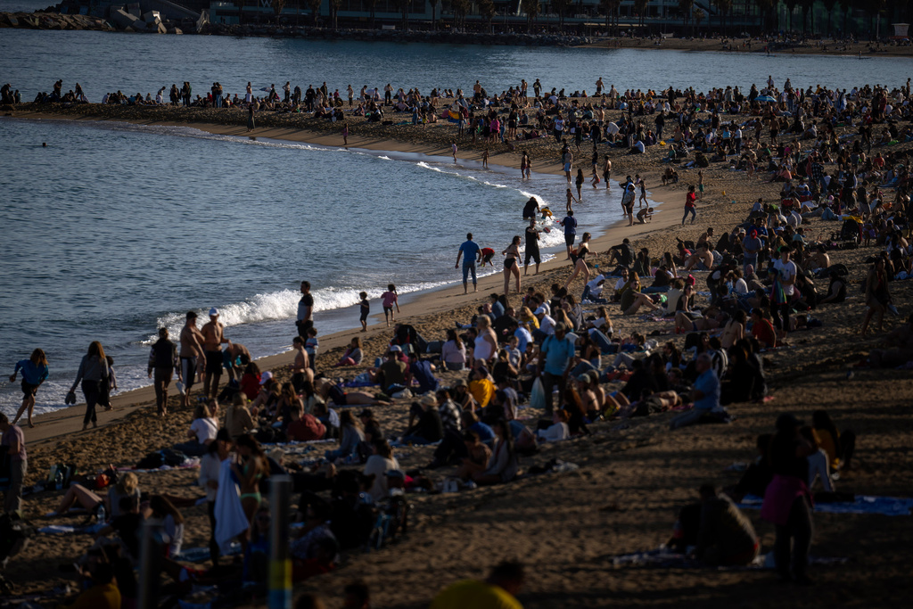 FILE - People sunbathe on a beach in Barcelona, Spain, Sunday, March 12, 2023. (AP Photo/Emilio Morenatti, File)