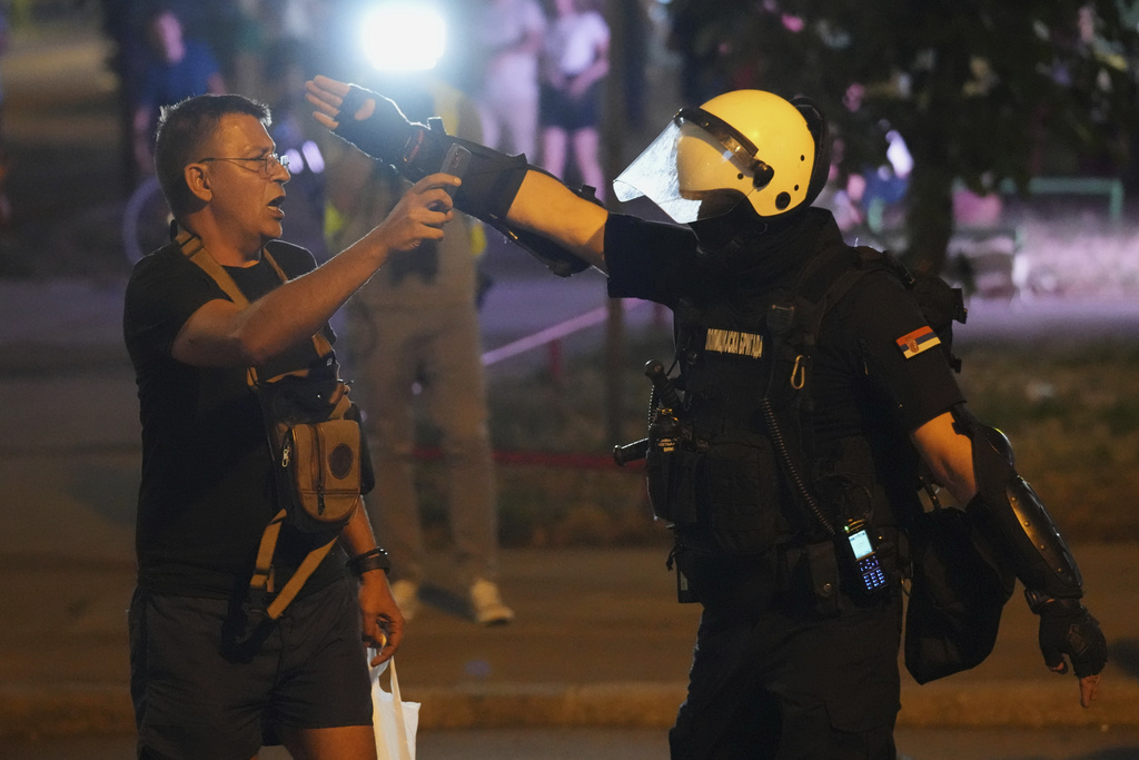 A Serbian riot police officer directs a man filming after clearing people blocking a street during an anti-government protest in Belgrade, Serbia, Saturday, Aug. 16, 2025. (AP Photo/Darko Vojinovic)