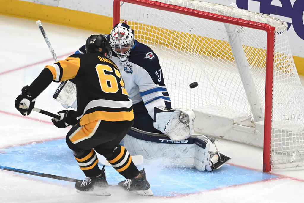 Pittsburgh Penguins right wing Rickard Rakell gets the puck past Winnipeg Jets goalie Connor Hellebuyck (37) for a goal during the first period in an NHL game, Saturday, March 21, 2026, in Pittsburgh. (AP Photo/Philip G. Pavely)