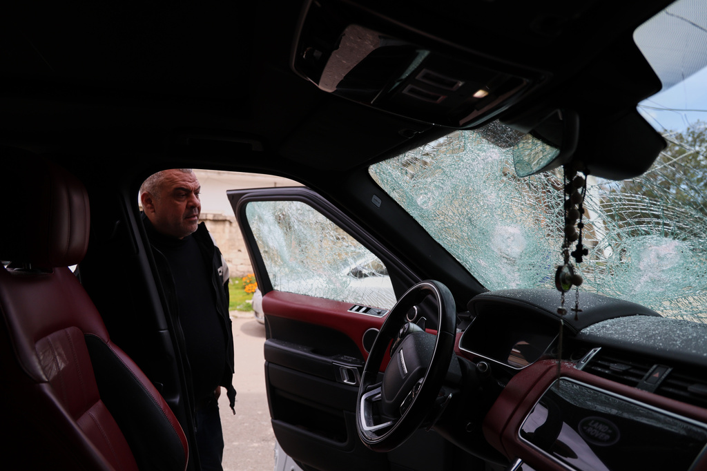 A man inspects a vehicle with shattered windows following overnight violence in the predominantly Christian town of Al-Suqaylabiyah, west of Hama, Syria, Saturday, March 28, 2026. (AP Photo/Omar Albam)