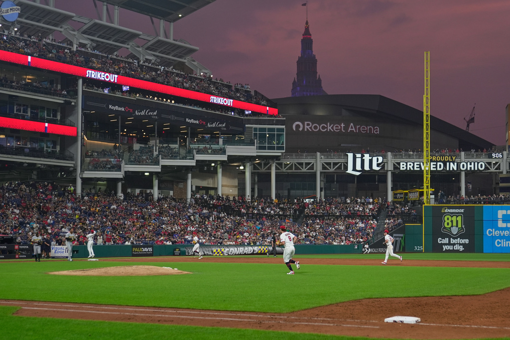 The Cleveland Guardians run off the field in the third inning of the second baseball game of a split doubleheader against the Pittsburgh Pirates as smoke filled skies return to Cleveland after rain delayed the start of the game in Cleveland, Saturday, June 18, 2026. (AP Photo/Sue Ogrocki)