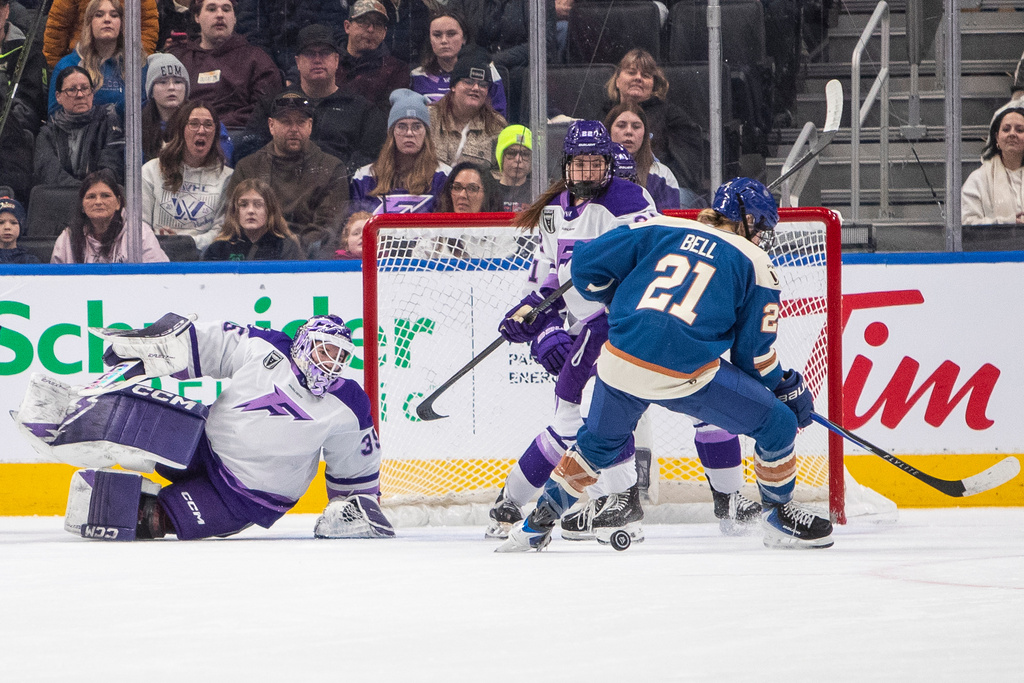 Minnesota Frost goalie Maddie Rooney (35) looks for the puck with teammate Natalie Buchbinder (22) and Vancouver Goldeneyes' Ashton Bell (21) during first-period PWHL hockey game action in Edmonton, Alberta, Saturday, Dec. 27, 2025. (Amber Bracken/The Canadian Press via AP)