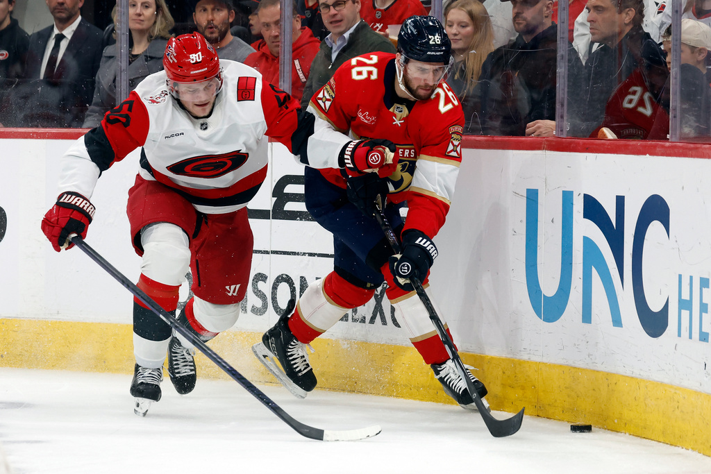 Florida Panthers' Uvis Balinskis (26) clears the puck in front of Carolina Hurricanes' Eric Robinson (50) during the second period of an NHL hockey game in Raleigh, N.C., Tuesday, Dec. 23, 2025. (AP Photo/Karl DeBlaker)