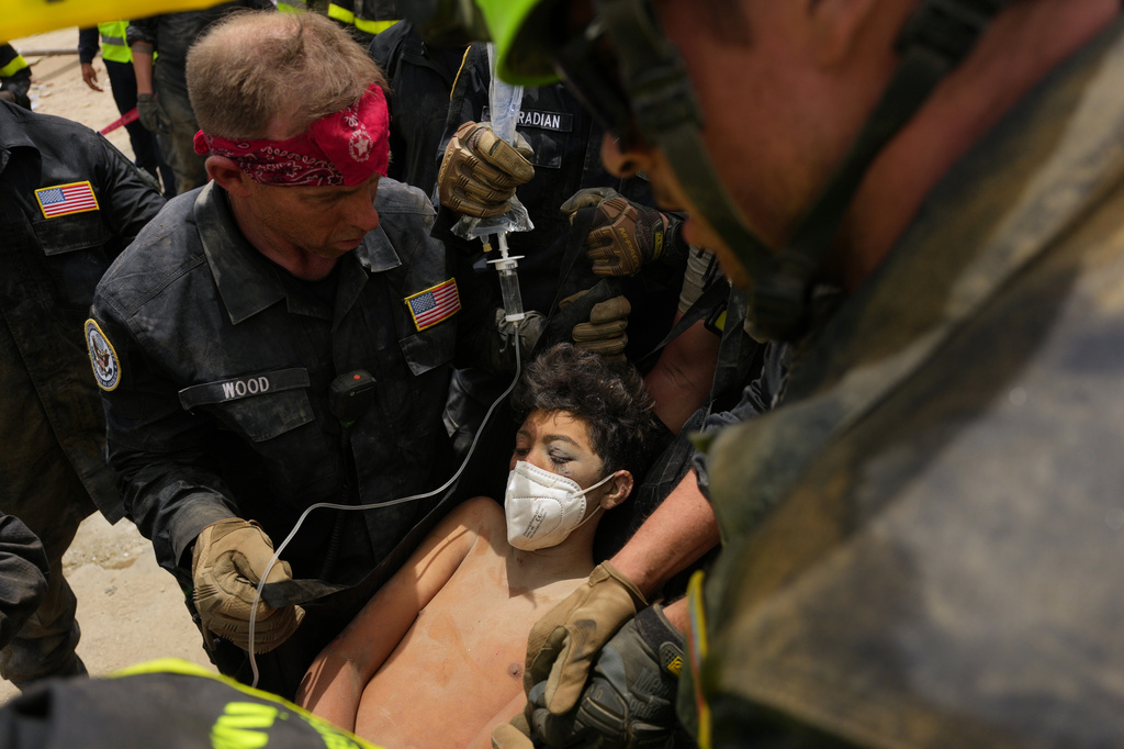 U.S. firefighters from the Fairfax County search and rescue team pull a boy from the rubble after rescuing him and his father from a building that collapsed in the earthquakes in La Guaira, Venezuela, Sunday, June 28, 2026. (AP Photo/Matias Delacroix)