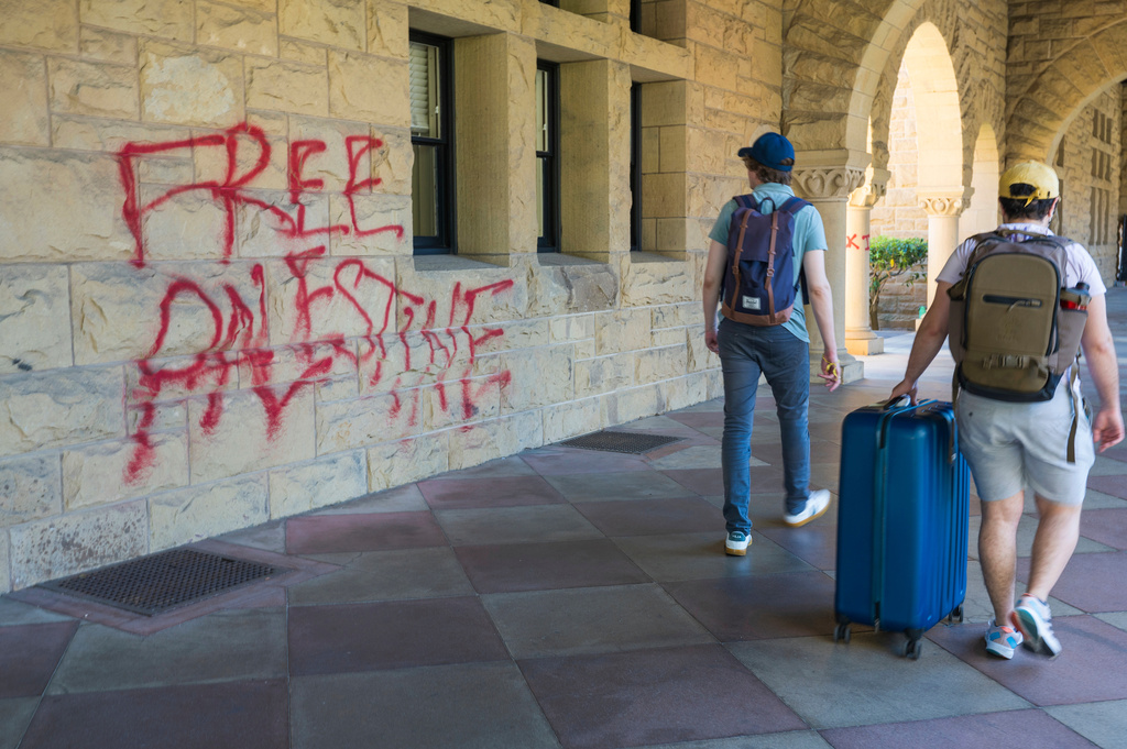 FILE - Students walk by graffiti near university president Richard Saller's office at Stanford University in Stanford, Calif., June 5, 2024. (AP Photo/Nic Coury, File)