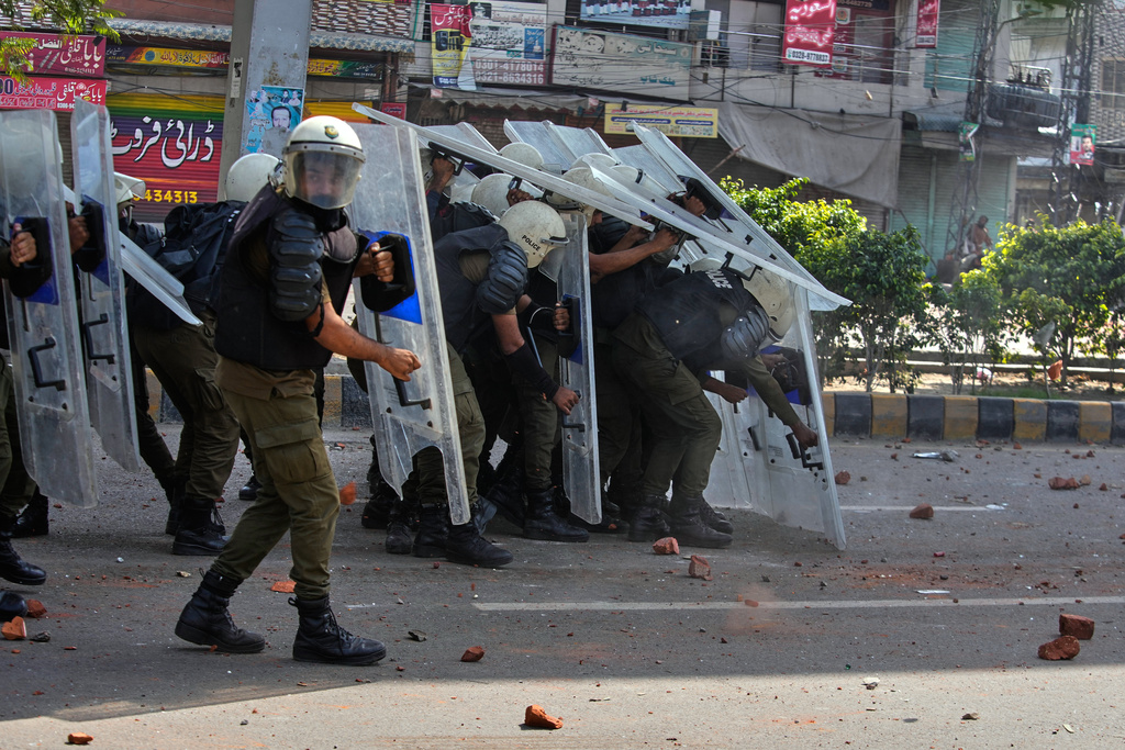 Police personnel take cover behind shields to save themselves from stones thrown by supporters of Islamist party 'Tehreek-e-Labbaik Pakistan' during clashes ahead of their pro-Palestinian march toward capital Islamabad, in Lahore, Pakistan, Friday, Oct. 10, 2025. (AP Photo/K.M. Chaudary)