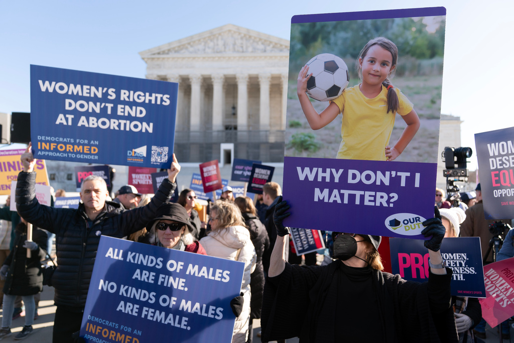 Protesters gather outside the Supreme Court as it hears arguments over state laws barring transgender girls and women from playing on school athletic teams, Tuesday, Jan. 13, 2026, in Washington. (AP Photo/Jose Luis Magana)