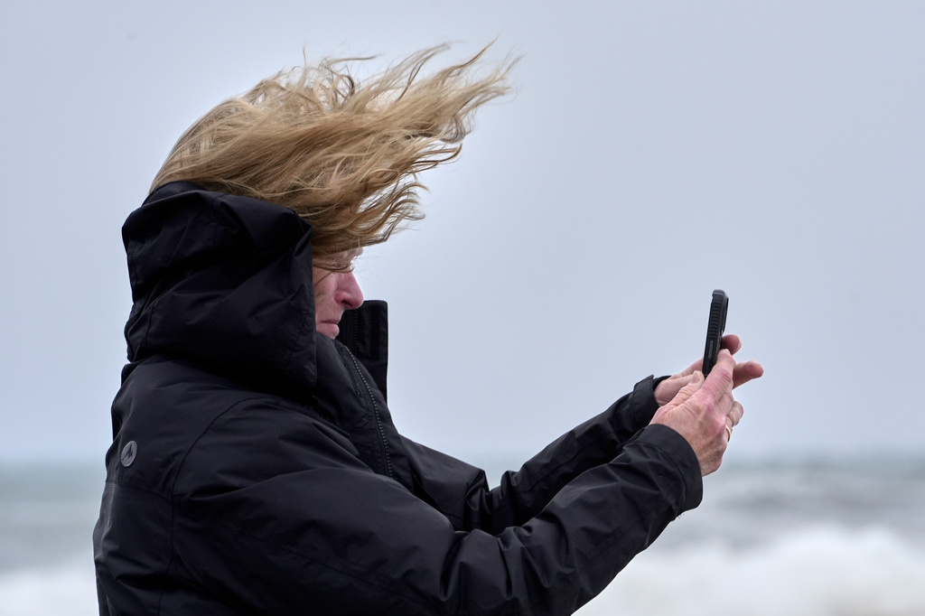 Denise Taylor of Manchester, N.H., is buffeted by the wind as she films the raging sea during a nor'easter storm in Hampton, N.H., Saturday, Sept. 26, 2026. (AP Photo/Robert F. Bukaty)