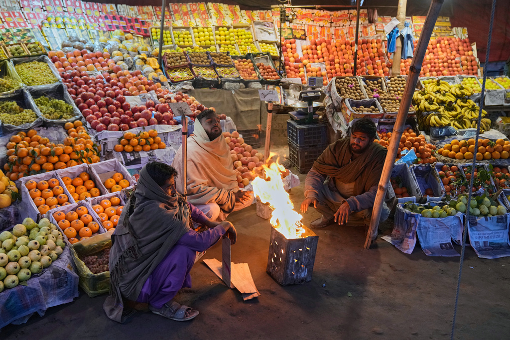 Vendors warm themselves around a fire on a cold morning in Lahore, Pakistan, Tuesday, Dec. 9, 2025. (AP Photo/K.M. Chaudary)