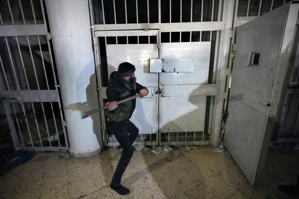 FILE - A man breaks the lock of a cell in the infamous Saydnaya military prison, just north of Damascus, Syria, Monday, Dec. 9, 2024. (AP Photo/Hussein Malla, File)