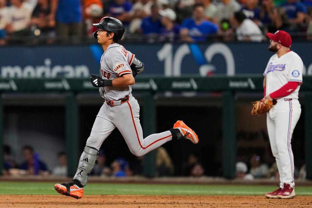 San Francisco Giants' Jung Hoo Lee, left, rounds the bases past Texas Rangers' Jake Burger, right, after Lee hit a solo home run in the third inning of a baseball game in Arlington, Texas, Monday, Aug. 3, 2026. (AP Photo/Tony Gutierrez)