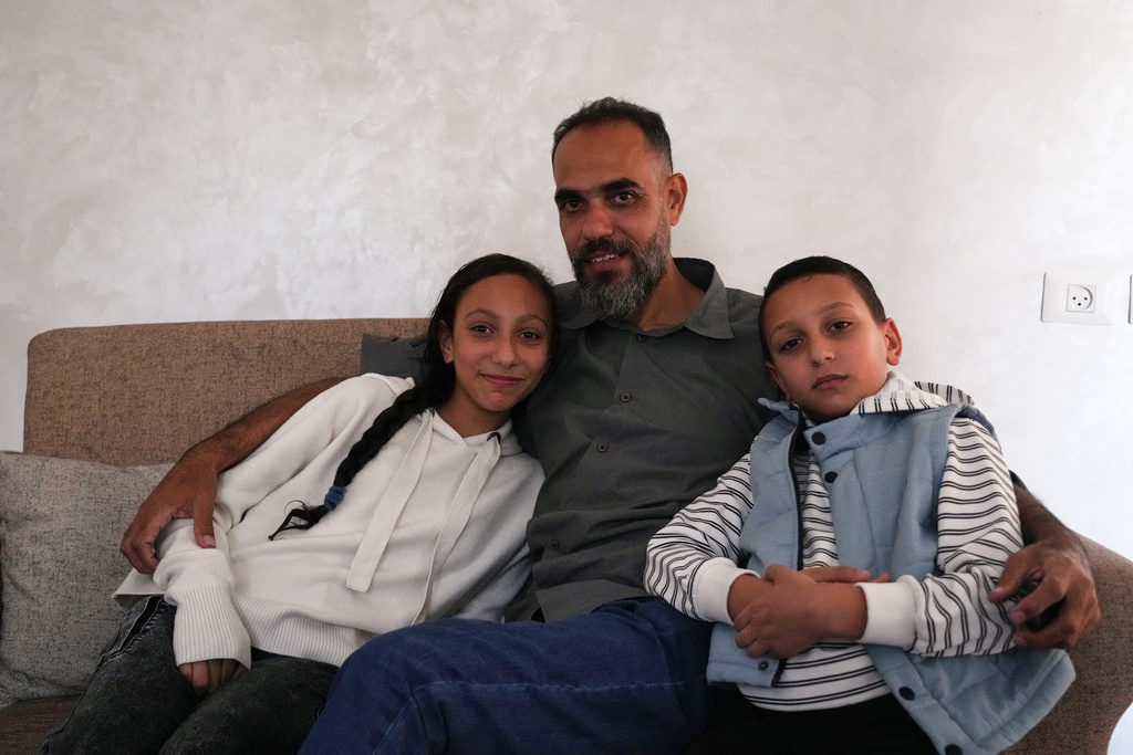 Palestinian medical technician Mohammed Abu Moussa, 45, who was released from Israeli detention after 20 months, poses for a photo with his children, Jourie and Hamid, in Deir al-Balah, Gaza, Saturday, Oct, 18, 2025. (AP Photo/Abdel Kareem Hana)