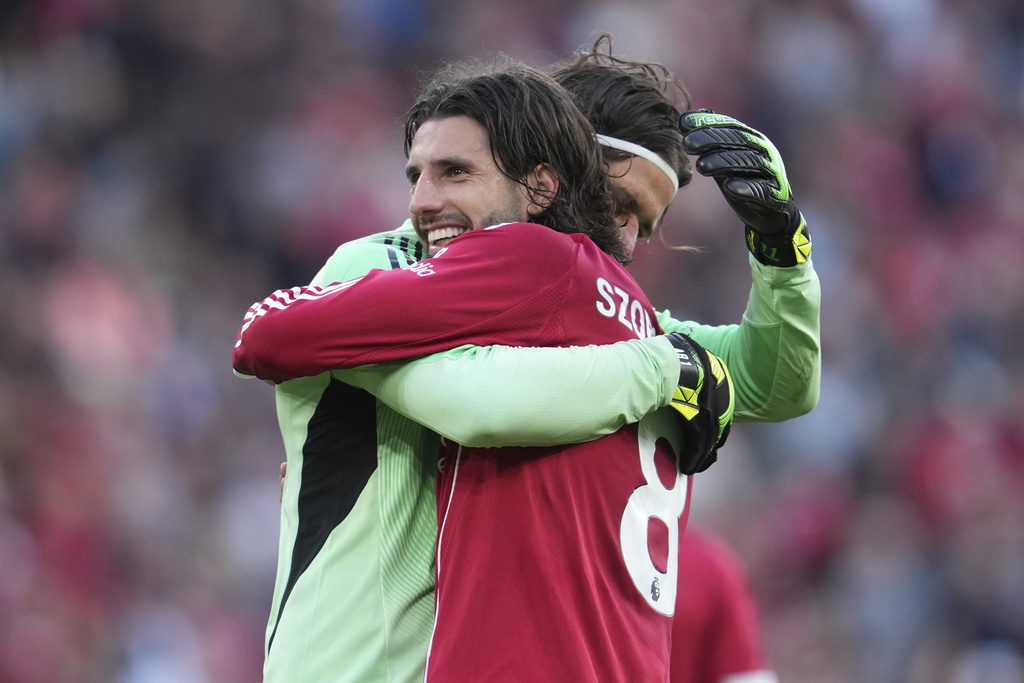 Liverpool's Dominik Szoboszlai celebrates with Liverpool's goalkeeper Alisson after the English Premier League soccer match between FC Liverpool and FC Arsenal in Liverpool, England, Sunday, Aug. 31, 2025. (AP Photo/Jon Super)