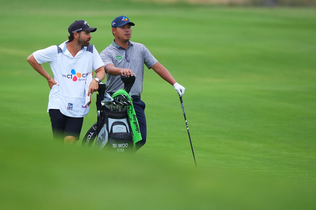Si Woo Kim, right, of South Korea, listens to his caddie Manuel Villegas before an approach shot on the 14th green during the first round of the Byron Nelson golf tournament in McKinney, Texas, Thursday, May 21, 2026. (AP Photo/LM Otero)