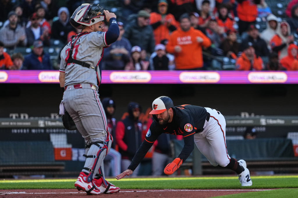 Baltimore Orioles' Colton Cowser, right, dives into home plate to score past Minnesota Twins catcher Ryan Jeffers, left, on an RBI single hit by Orioles' Jeremiah Jackson during the second inning of a baseball game, Saturday, March 28, 2026, in Baltimore. (AP Photo/Stephanie Scarbrough)