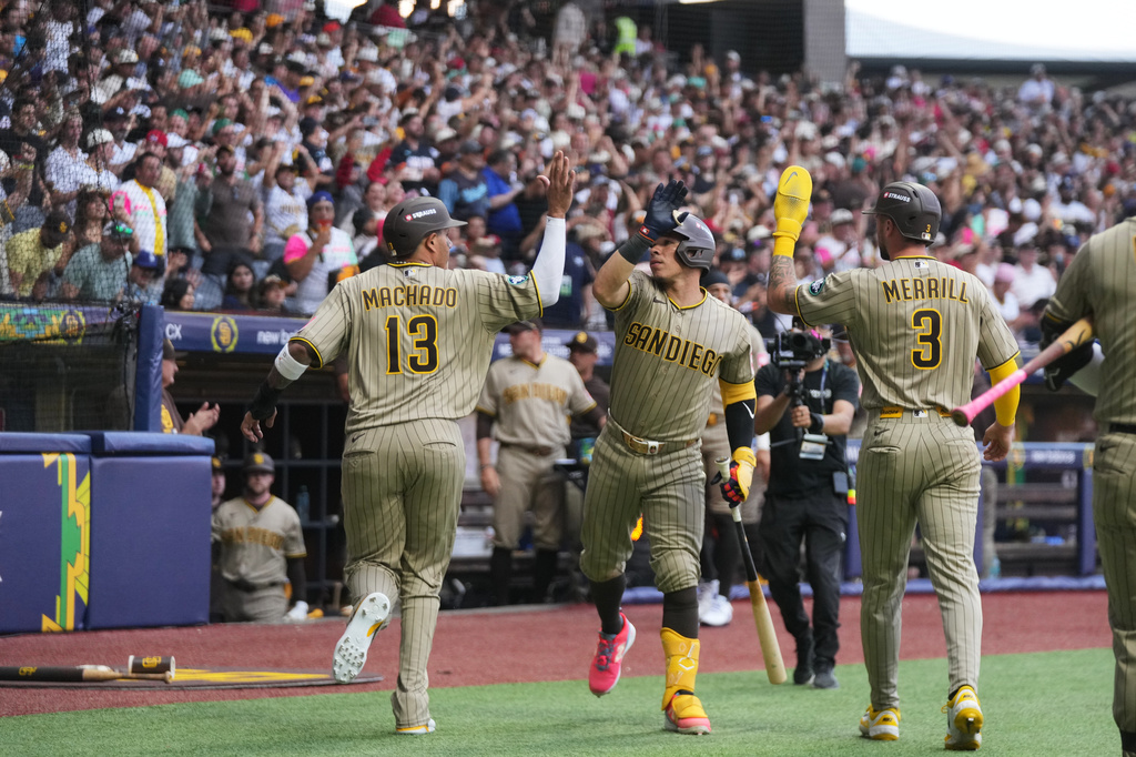 San Diego Padres' Manny Machado, left, is congratulated after scoring against the Arizona Diamondbacks during the seventh inning of a baseball game in Mexico City, Saturday, April 25, 2026. (AP Photo/Fernando Llano)