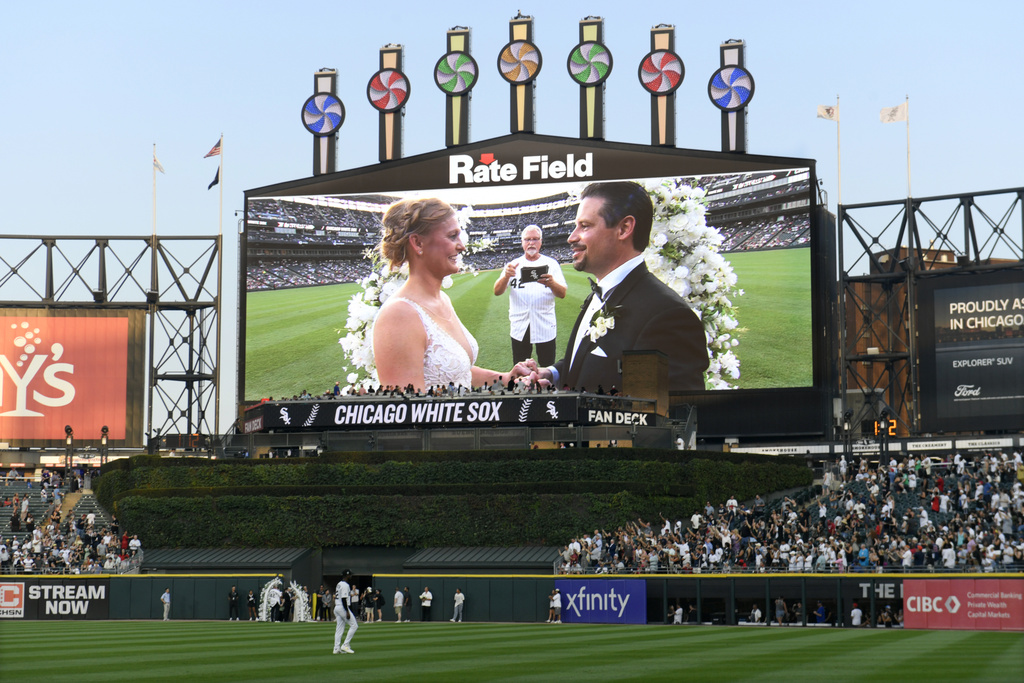 Two lifelong Chicago White Sox fans exchange wedding vows during a 60-second wedding officiated by former White Sox player and 1983 rookie of the year Ron Kittle at a baseball game between the White Sox and the Cleveland Guardians, Saturday, Aug. 9, 2025, in Chicago. (AP Photo/Paul Beaty)