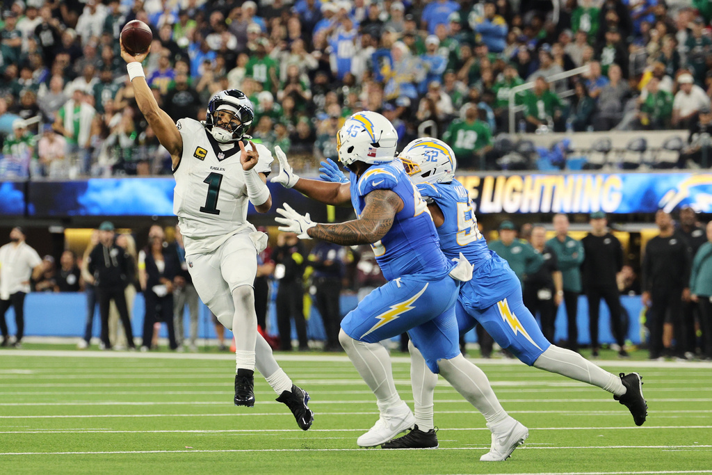 Philadelphia Eagles quarterback Jalen Hurts (1) throws under pressure from Los Angeles Chargers outside linebacker Khalil Mack (52) and linebacker Tuli Tuipulotu (45) during the first half of an NFL football game Monday, Dec. 8, 2025, in Inglewood, Calif. (AP Photo/Kevork Djansezian)