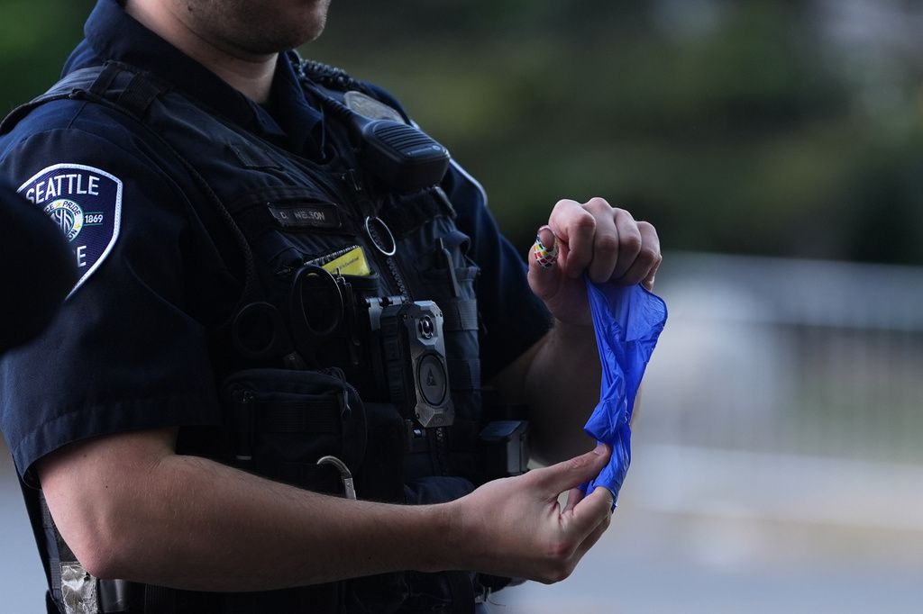 A police officer puts a bullet casing into a rubber glove after he received it from a person who found it, following a shooting at Seattle Center during the Bite of Seattle food festival, Monday, July 27, 2026, in Seattle. (AP Photo/Lindsey Wasson)