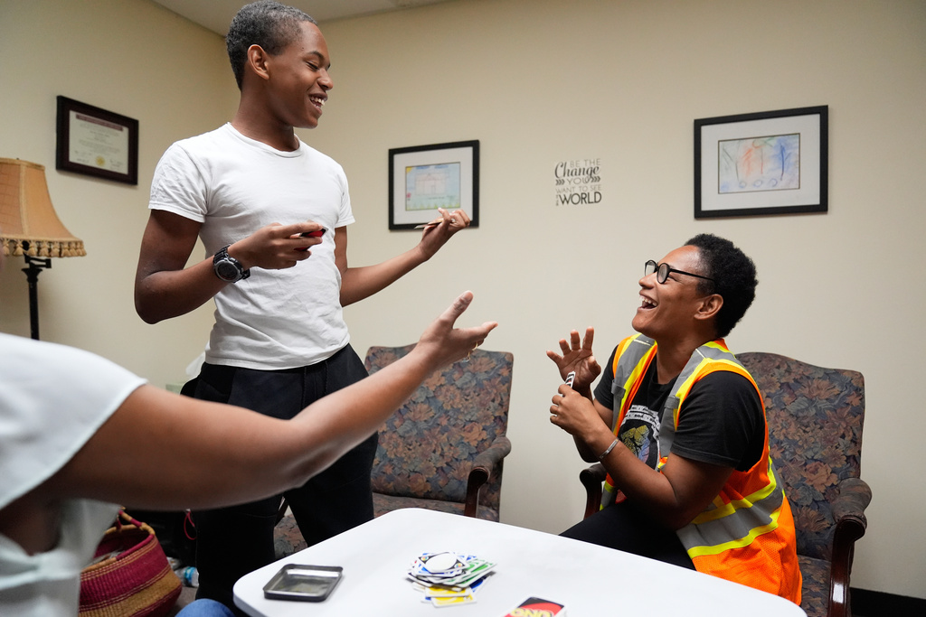 Elias Washington, left, laughs with his mother, Sechita McNair, right, in family therapy as they play a card game on June 9, 2025, in Decatur, Ga. (AP Photo/Brynn Anderson)
