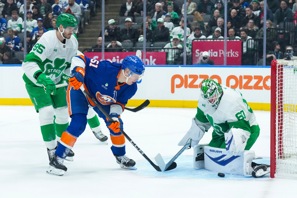 New York Islanders' Emil Heineman, center, shoots on Toronto Maple Leafs goaltender Joseph Woll during the first period of an NHL hockey game in Toronto, Tuesday March 17, 2026. (Chris Young/The Canadian Press via AP)