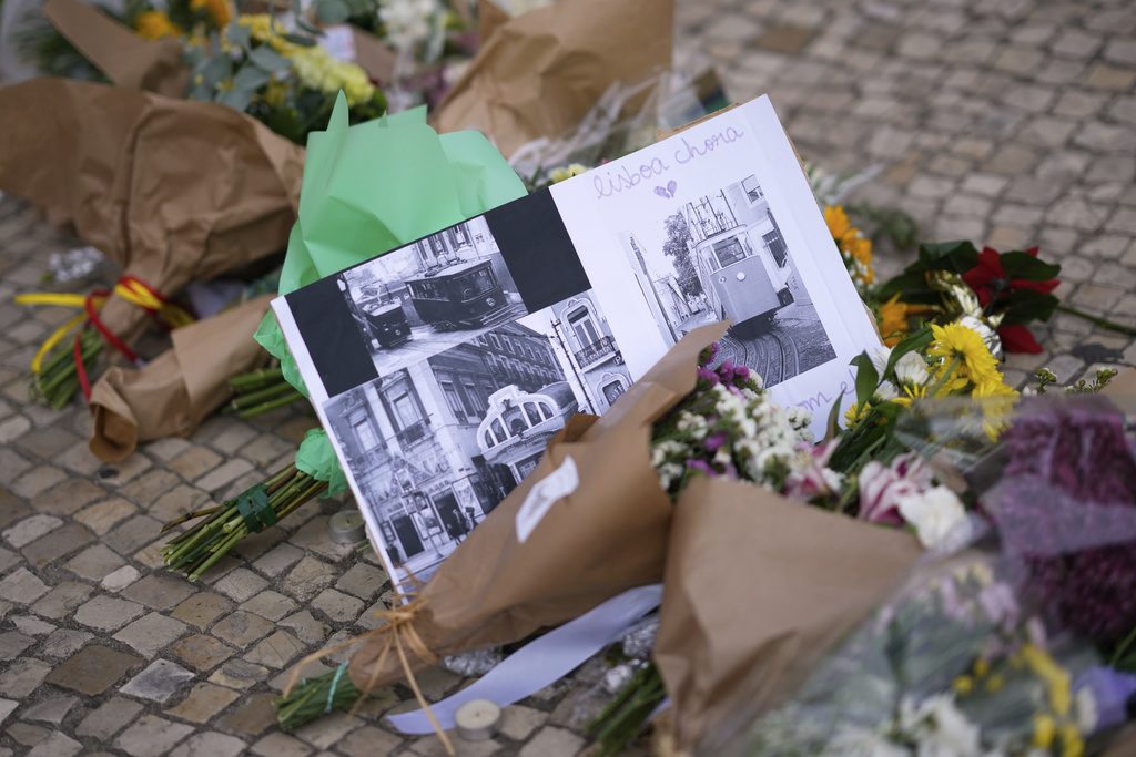 Images of streetcars with messages placed next to flowers, are photographed at the site where a tourist streetcar derailed and crashed in Lisbon, Portugal, Friday, Sept. 5, 2025. (AP Photo/Armando Franca)