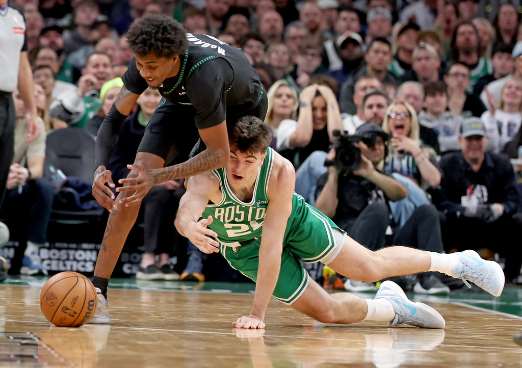 Minnesota Timberwolves forward Jaden McDaniels, left, and Boston Celtics forward Hugo González, right, trip each other up chasing the ball during the first half of an NBA basketball game, Sunday, March 22, 2026, in Boston. (AP Photo/Mark Stockwell)