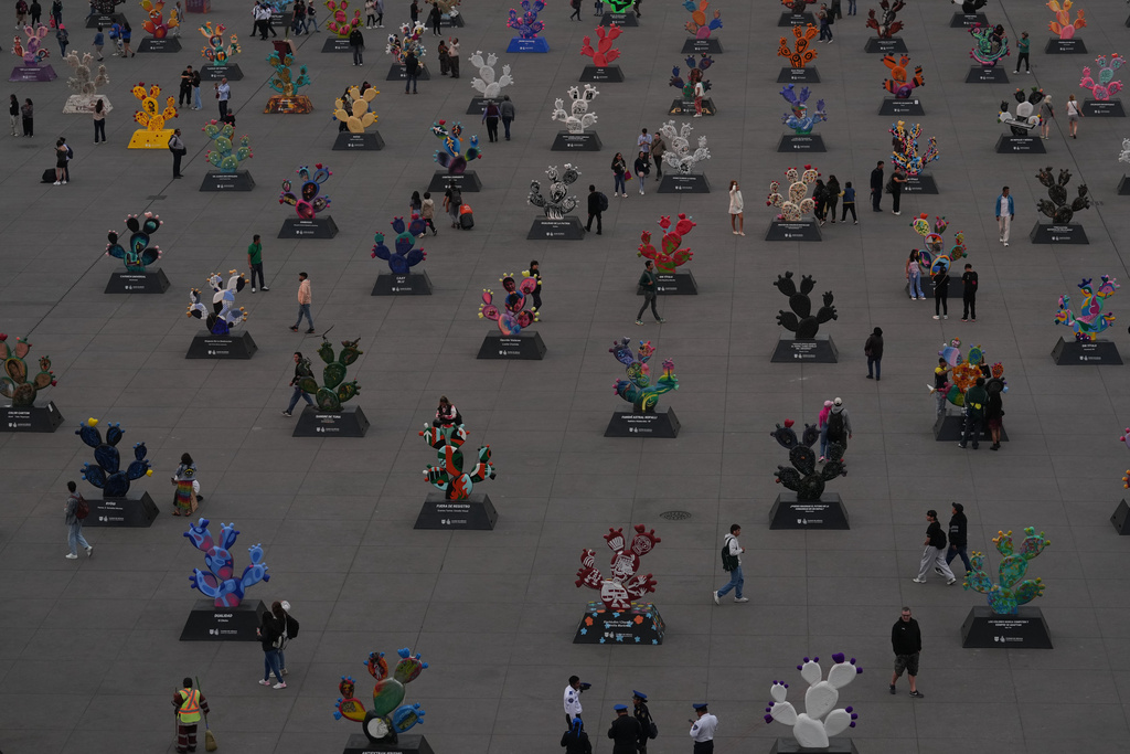 People walk among structures of nopales, prickly pear cacti, at the National Palace in Mexico City's main square, the Zócalo, Tuesday, Jan. 27, 2026. (AP Photo/Marco Ugarte)