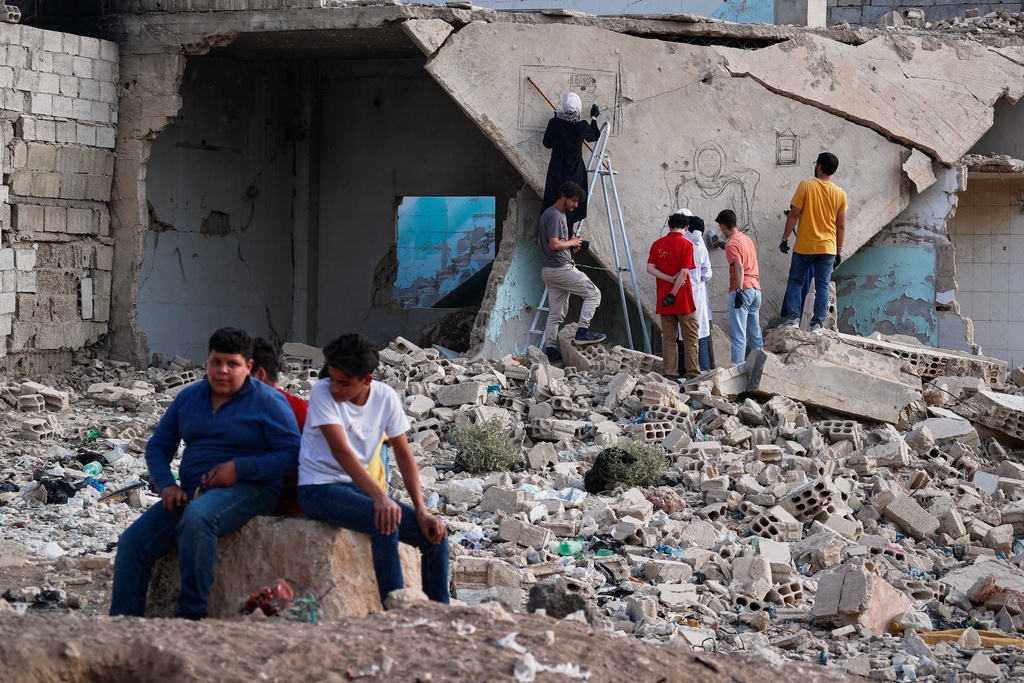 A group of Syrian graffiti artists sketch a mural on the collapsed ceiling of a war-damaged house in Daraya, on the outskirts of Damascus, Syria, Monday, Nov. 3, 2025. (AP Photo/Omar Sanadiki)