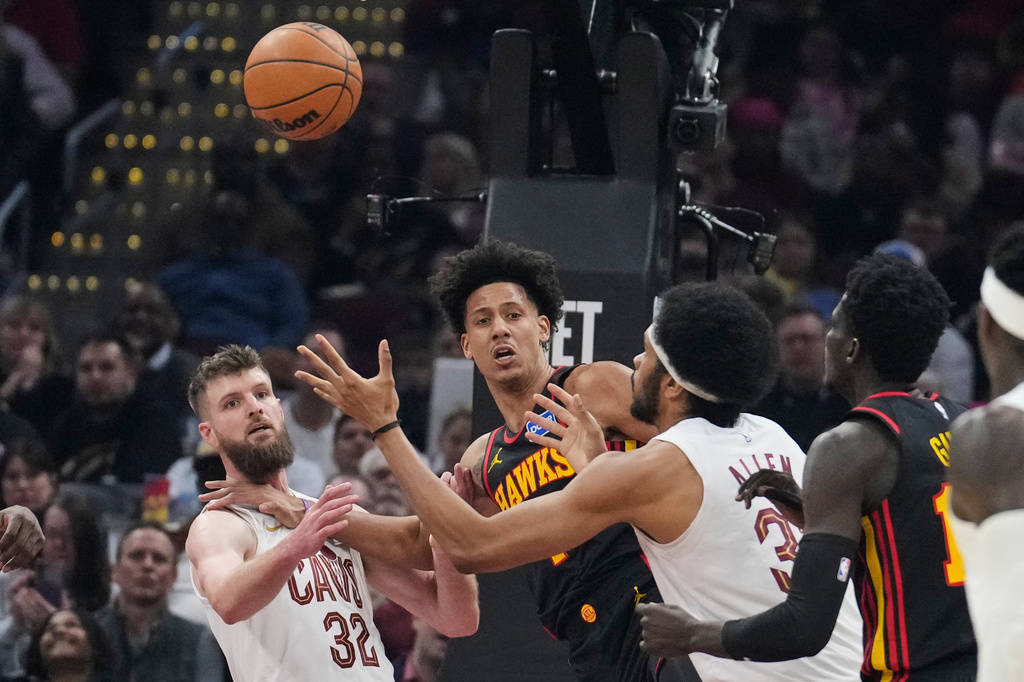 Cleveland Cavaliers center Jarrett Allen, right, reaches for the ball with teammate Dean Wade (32) and Atlanta Hawks forward Jalen Johnson, center, in the first half of an NBA basketball game in Cleveland, Wednesday, April 8, 2026. (AP Photo/Sue Ogrocki)