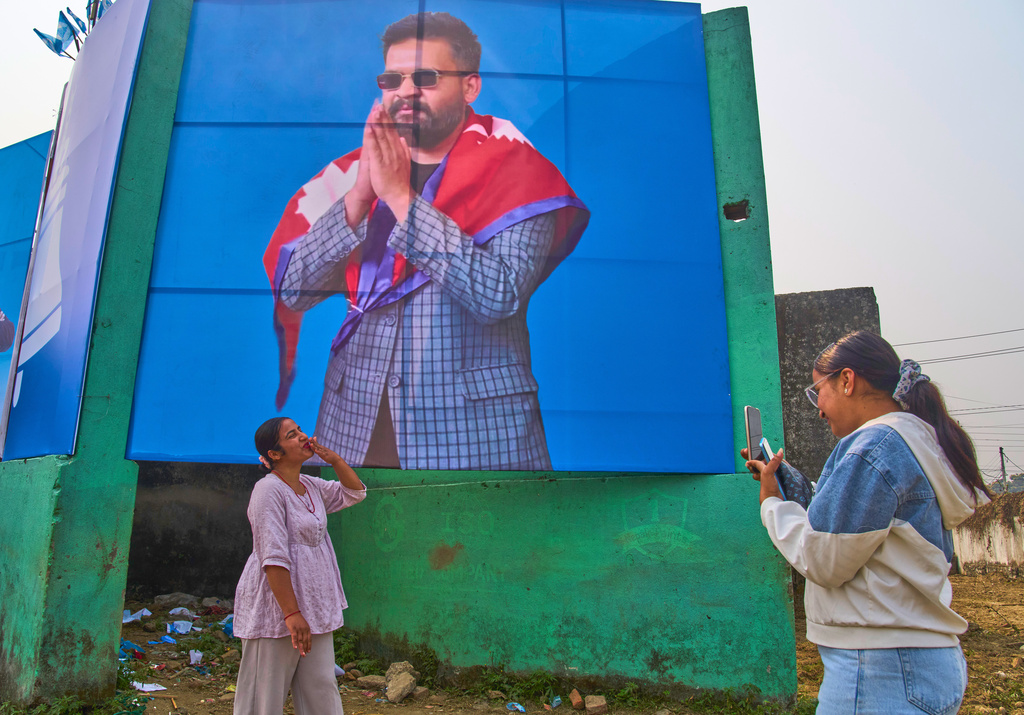 A Rastriya Swatantra Party supporter photographs a friend in front of a large banner depicting party leader Balendra Shah during an election rally in Chitwan, approximately 180 kilometers (112 miles) west of Kathmandu, Nepal, Friday, Feb. 27, 2026. (AP Photo/Niranjan Shrestha)