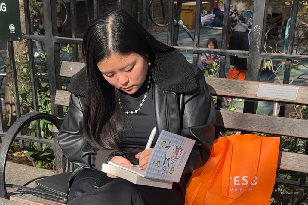 Kim Ventresca, 22, writes in a journal at Union Square Park in Manhattan on Nov. 6, 2025. (AP Photo/Cathy Bussewitz)